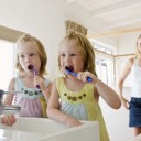 Mother and twin girls brushing teeth